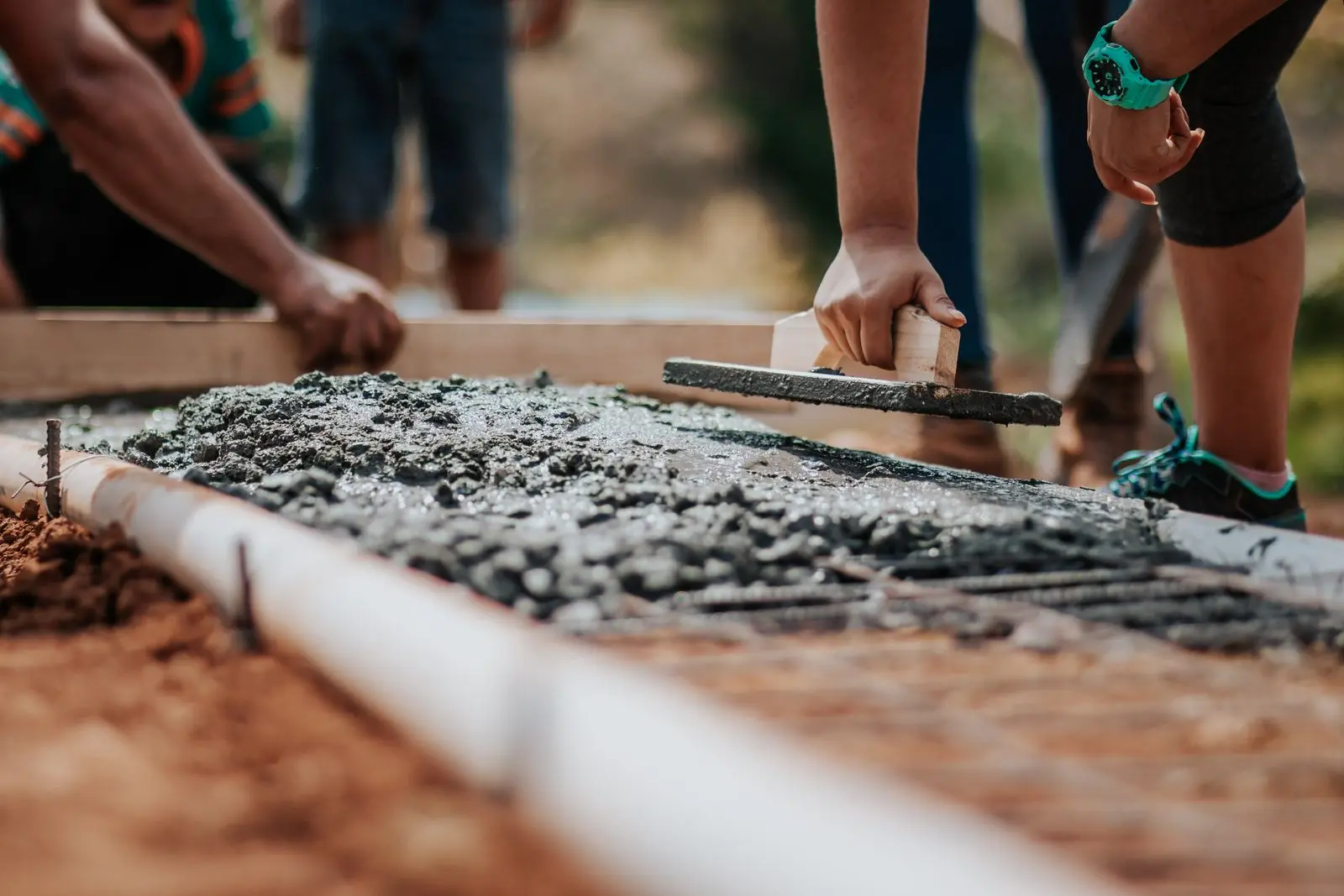 Workers levelling fresh concrete over steel reinforcement