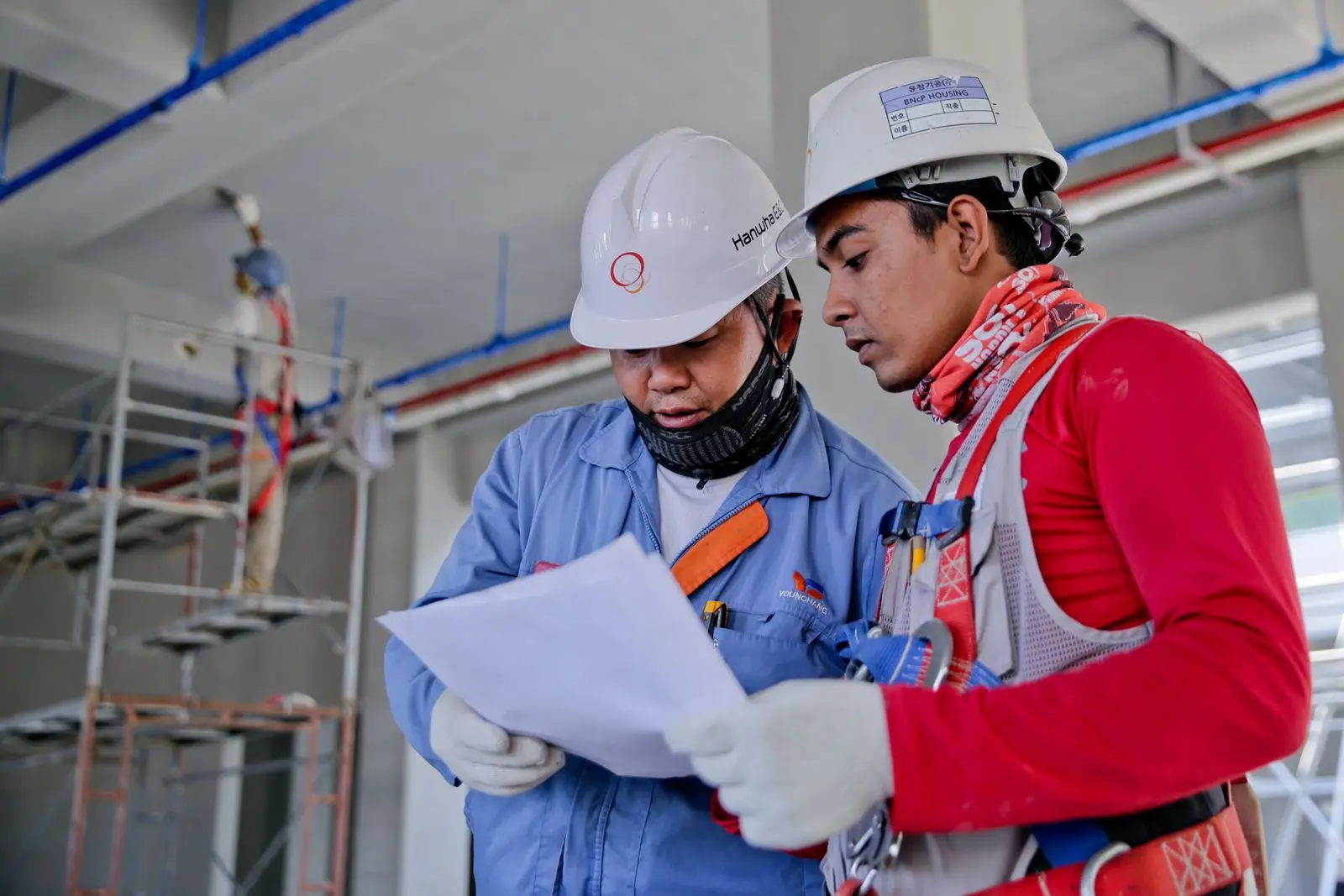 Site engineers in safety helmets reviewing construction drawings together